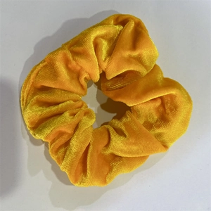 Dettaglio macro dell'elastico per capelli in velluto giallo zenzero con pieghe