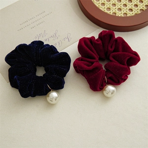 Detail of velvet scrunchies with pearls in navy and burgundy on a vintage tray