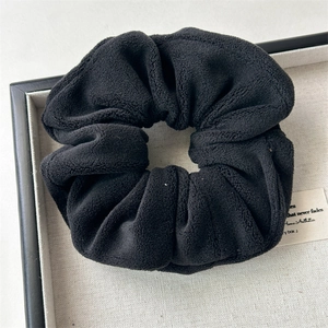 Close-up of black plush velvet scrunchie showing soft texture and high elastic material