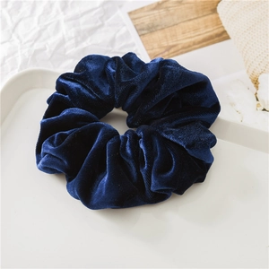 Dettaglio di un elastico per capelli in velluto blu scuro con morbida texture a pieghe