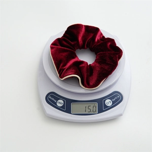 Minimalist burgundy velvet hair scrunchie with cream trim weighing 15.0g on a digital scale