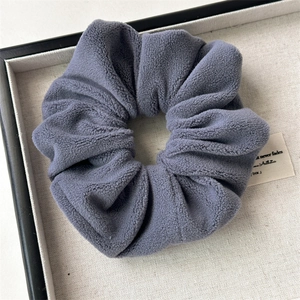 Detailed view of dusty blue plush scrunchie with soft velvet texture on display tray