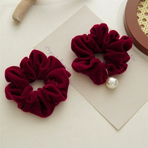 Macro detail of two vintage burgundy velvet hair scrunchies with white pearl pendant