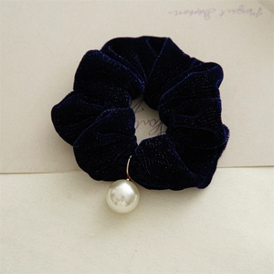 Macro detail of navy velvet hair scrunchie with shiny finish and a large pearl pendant