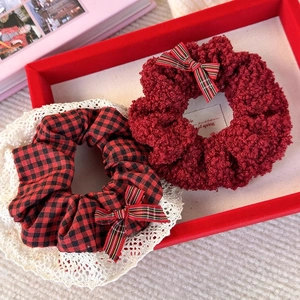 Detail of red plush and plaid bow hair scrunchies with white lace trim for festive styling