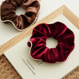 Detail view of burgundy and brown velvet scrunchies with white piping on a vintage book