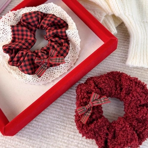 Detail of red lamb wool and plaid cotton scrunchies with bow and lace trim