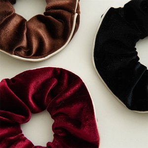 Detail of velvet hair scrunchies in brown, burgundy and black with white trim edges