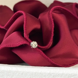 Detail of burgundy satin scrunchie featuring fine pleats and a sparkling rhinestone