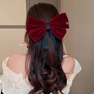 Elegant burgundy velvet bow hair clip with black ribbon details on model back view