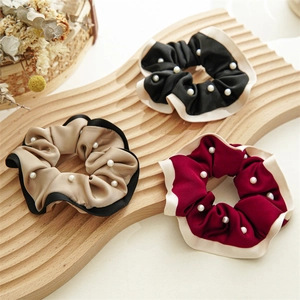 Close-up of velvet hair scrunchies with pearls in black, brown and burgundy colors