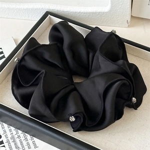 Detail of black satin scrunchie with rhinestones on a minimalist display box