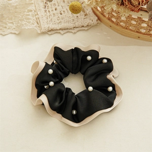 Detail of elegant black velvet hair scrunchie with cream ruffles and faux pearl beads