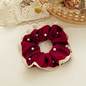Detail of burgundy velvet scrunchie with cream wavy edges and decorative white pearls