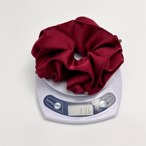 Detail view of burgundy satin scrunchie with silver beads weighing 33.6g on a scale