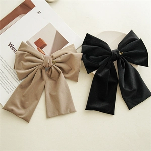 Close-up of khaki and black oversized velvet bow hair clips with elegant gold metal pendants