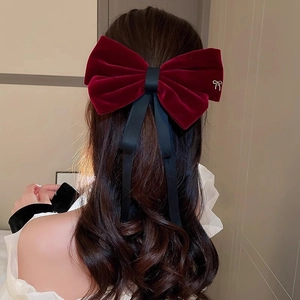 Detail view of a large burgundy velvet bow hair clip with black ribbons and silver butterfly