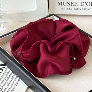 Close-up of burgundy satin scrunchie with sparkling rhinestones on a stylish tray