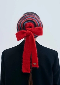 Close-up of red knit bow hair scrunchie with colorful stripes and soft wool texture