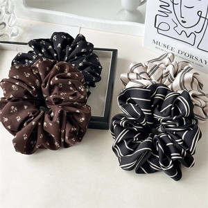 Detail of four floral and striped fabric hair scrunchies displayed with artistic books