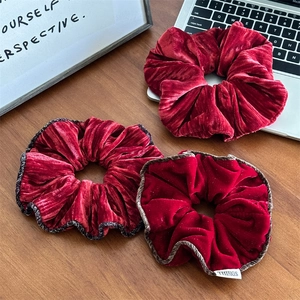 Détail de chouchous en velours rouge avec bordure élégante sur un bureau en bois