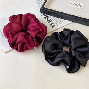 Detail of luxury satin scrunchies in wine red and black with sparkly rhinestone accents