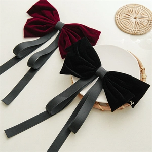 Close-up of elegant black velvet bow hairclip with gold metallic charm and long ribbons