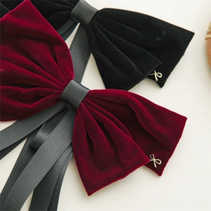 Detail of velvet bow hair clips with gold metal pendants in black and burgundy