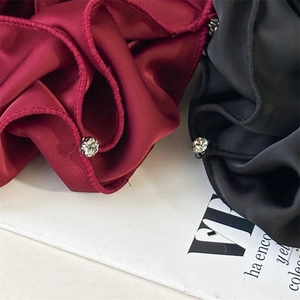 Detail of luxury satin scrunchies in wine red and black with sparkly rhinestone edges