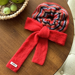 Detailed view of red knitted bow scrunchie with striped pattern and Nice woven label