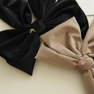 Close-up of velvet bow hair clips with gold Amy script metal initials and rich texture
