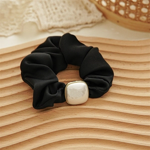 Close-up of velvet scrunchie with a large square faux pearl and golden metal edge detail