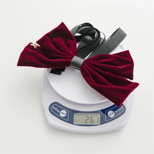 Burgundy velvet bow hair clip on a digital scale showing weight of 26.1 grams