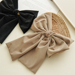 Detail of elegant black and khaki velvet bow hair clips with gold metal letter accents
