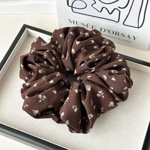 Detail of dark brown floral scrunchie with white prints on an artistic tray