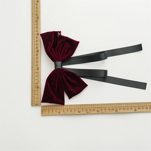 Detail shot of a handmade burgundy velvet bow with black ribbons and measuring ruler