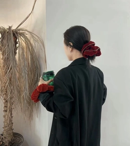 Détail d'un chouchou géant en velours rouge avec liseré fin sur cheveux et poignet