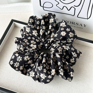 Detail of elegant black floral scrunchie with cream flowers on a decorative tray