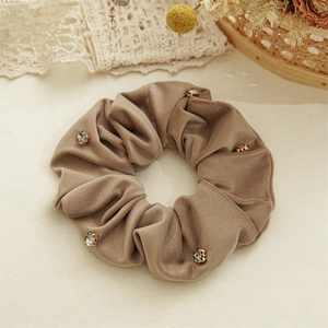 Macro shot of brown velvet scrunchie with sparkling rhinestones on vintage lace background