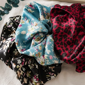 Trois chouchous en satin à motifs fleurs et léopard sur un fond en tissu blanc