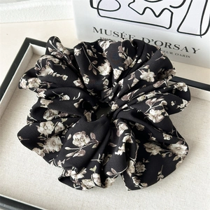 Close-up of a large floral scrunchie with vintage patterns on a fabric display tray