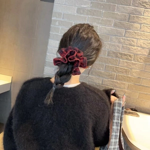 Detail of red plaid scrunchie with rhinestones worn on a hair bun by a model