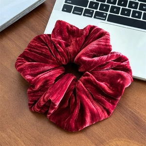 Détail d'un grand chouchou en velours rouge foncé montrant la texture douce et l'élastique