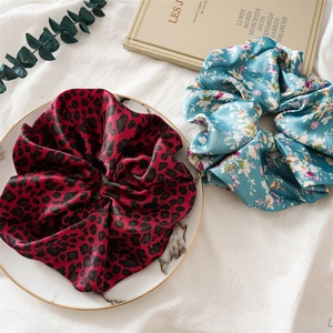 Détail de chouchous en satin imprimé léopard rouge et fleurs bleues sur plateau