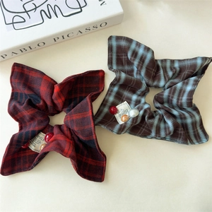 Detailed macro of red plaid scrunchies with decorative beads and smile fabric label