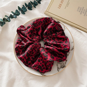 Détail d'un chouchou en satin rouge à motif léopard avec une texture soyeuse élégante
