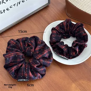 Detail view of a large red plaid scrunchie with white dots, showing its 15cm outer diameter