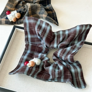 Detailed close-up of checkered scrunchies with smooth bead accents in a display tray