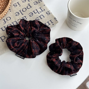 Detailed view of red plaid scrunchies with white dots and small black woven label