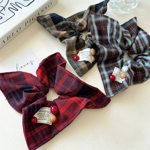 Close-up of three plaid scrunchies with decorative beads and vintage woven labels